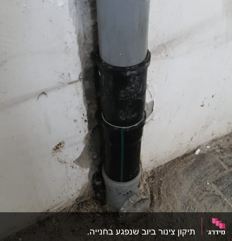 צינור ביוב מותקן בקיר עם טיח מתקלף